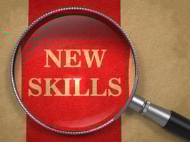 a magnifying glass over the words "new skills," symbolizing that really learning something involves experiencing it beyond consuming the content. the see one do one teach one method works for real learning
