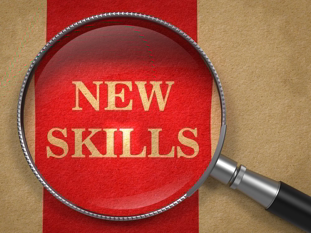 a magnifying glass over the words "new skills," symbolizing that really learning something involves experiencing it beyond consuming the content. the see one do one teach one method works for real learning
